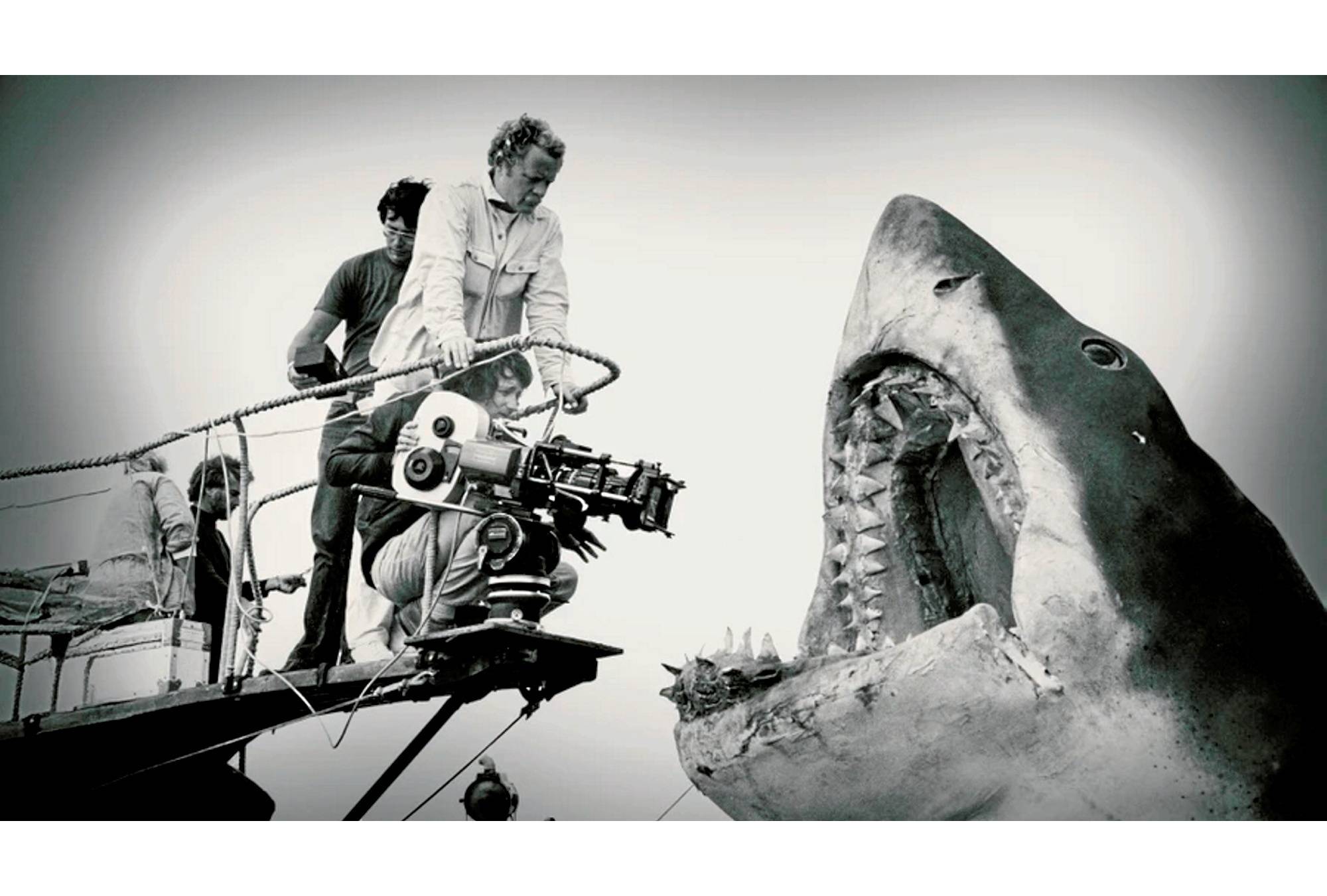 Photo en noir et blanc d'un faux requin sur le tournage avec un caméraman