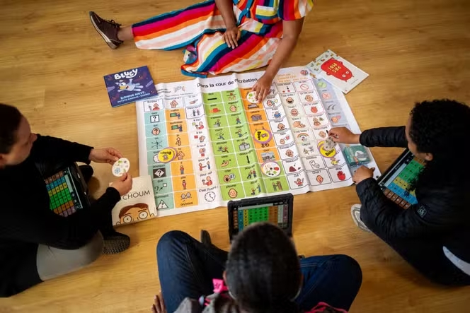 Personnes assises jouant à un jeu de société en pictogrammes avec des tablettes et des livres