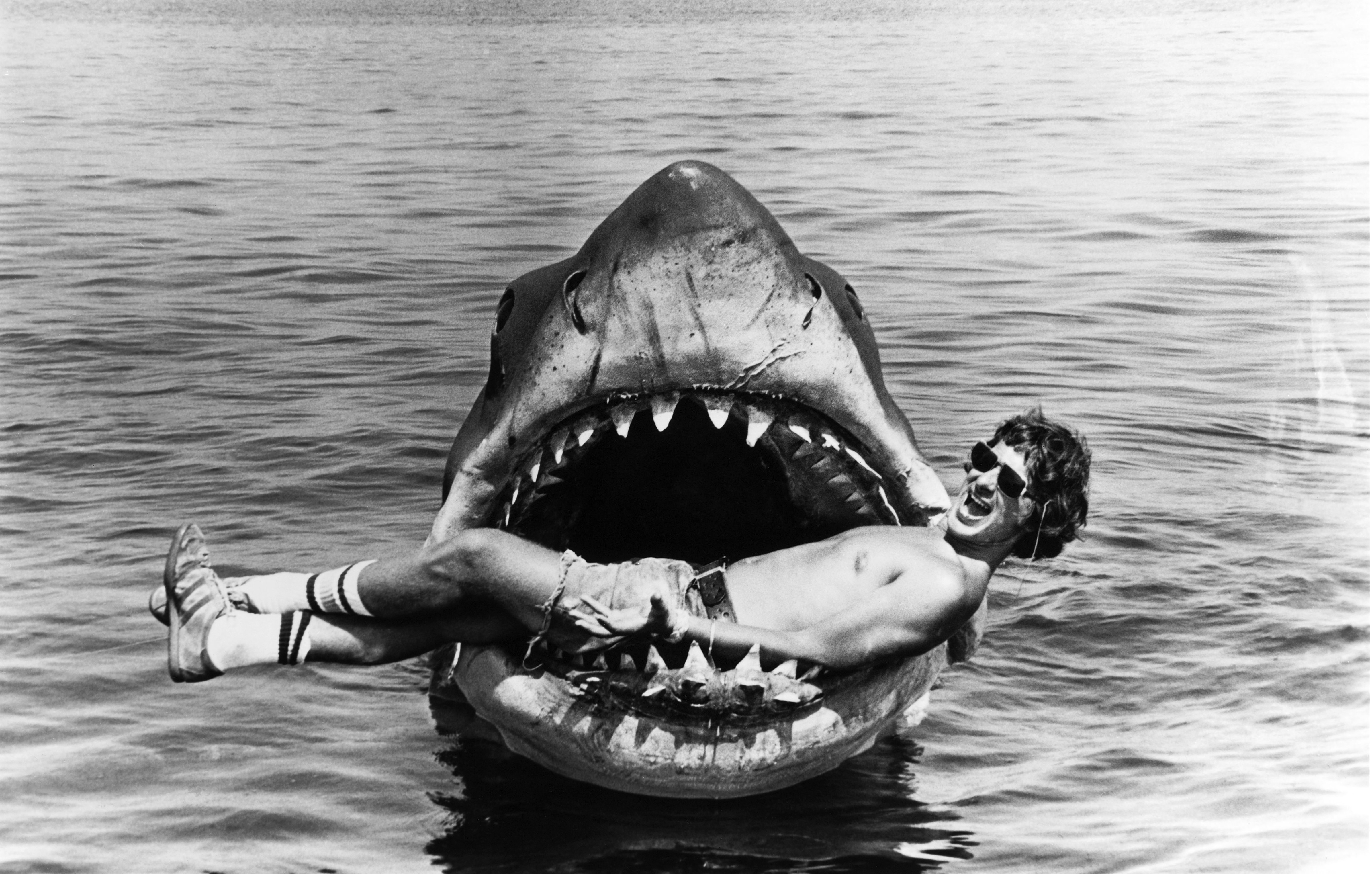 Photo en noir et blanc montrant Steven Spielberg dans la gueule d'un faux requin